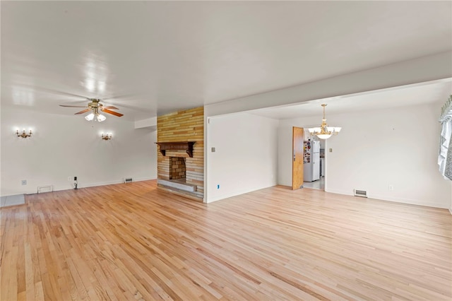 unfurnished living room featuring a stone fireplace, ceiling fan with notable chandelier, and light hardwood / wood-style floors