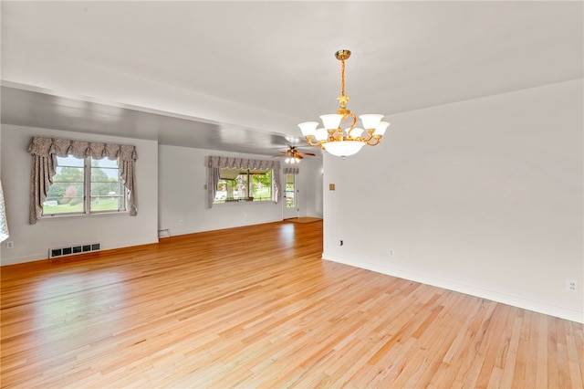 unfurnished room featuring light hardwood / wood-style floors, ceiling fan with notable chandelier, and plenty of natural light