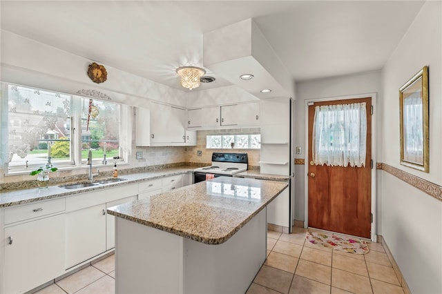 kitchen featuring white cabinets, a center island, electric range, and a wealth of natural light