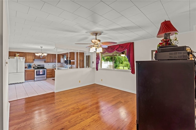 kitchen with kitchen peninsula, stainless steel electric range, light wood-type flooring, and white refrigerator