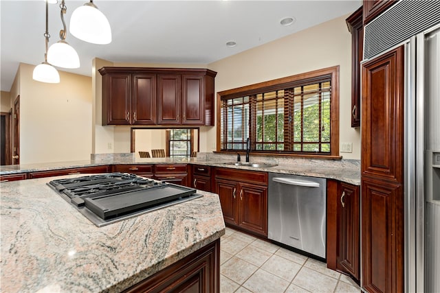 kitchen featuring light tile patterned floors, appliances with stainless steel finishes, light stone countertops, sink, and decorative light fixtures