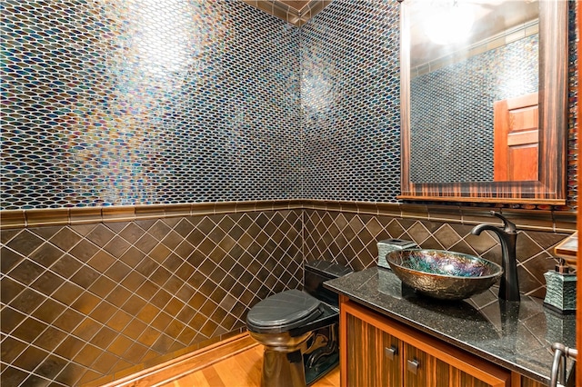 bathroom with vanity, toilet, tile walls, and hardwood / wood-style floors