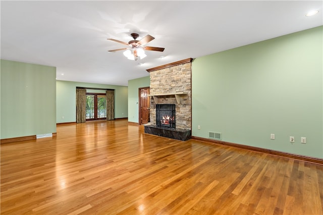 unfurnished living room featuring a stone fireplace, light wood-type flooring, and ceiling fan