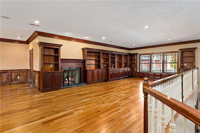 unfurnished living room featuring ornamental molding and light wood-type flooring