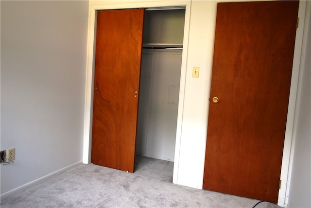 unfurnished bedroom with light colored carpet and a closet