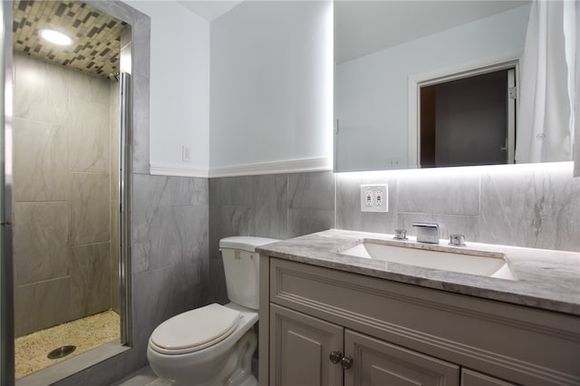 bathroom with vanity, toilet, walk in shower, and tile walls