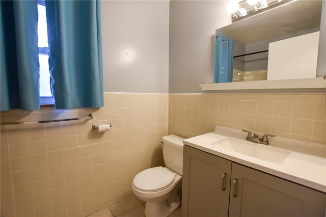 bathroom featuring tile patterned floors, toilet, vanity, a shower, and tile walls