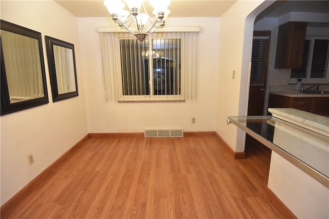 unfurnished dining area with light hardwood / wood-style flooring and an inviting chandelier