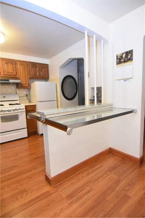 kitchen with decorative backsplash, light hardwood / wood-style flooring, and white appliances