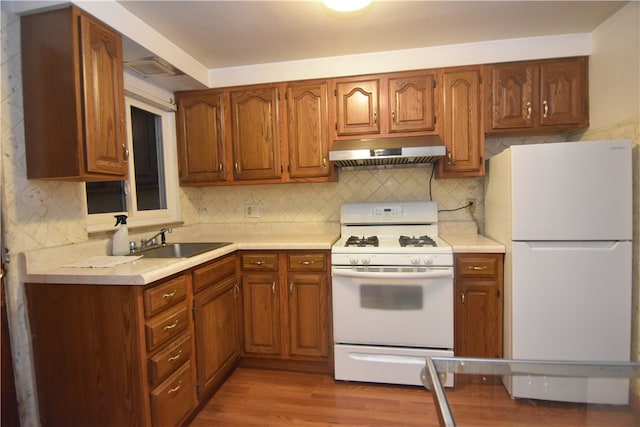 kitchen featuring tasteful backsplash, white appliances, sink, and light hardwood / wood-style flooring