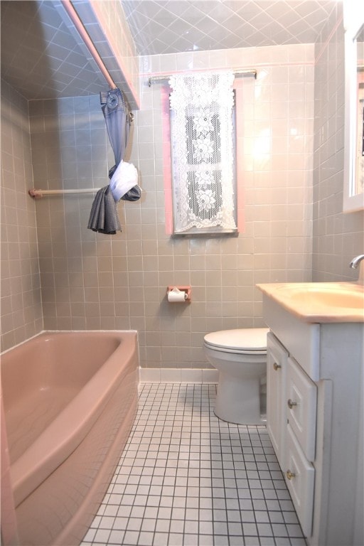 full bathroom featuring tile patterned floors, vanity, tiled shower / bath combo, tile walls, and toilet