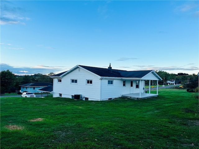 rear view of property featuring cooling unit and a lawn