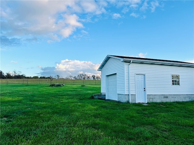 view of outdoor structure featuring a garage, a lawn, and a rural view