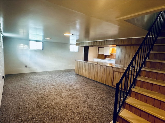 basement featuring carpet floors, wooden walls, and plenty of natural light