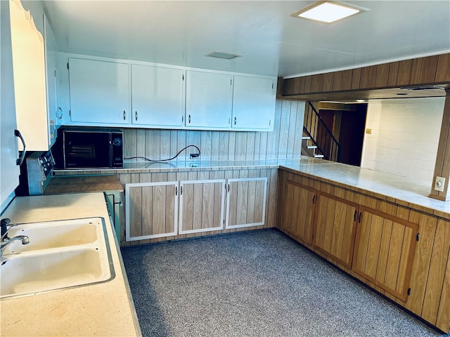 kitchen featuring sink, kitchen peninsula, and white cabinets