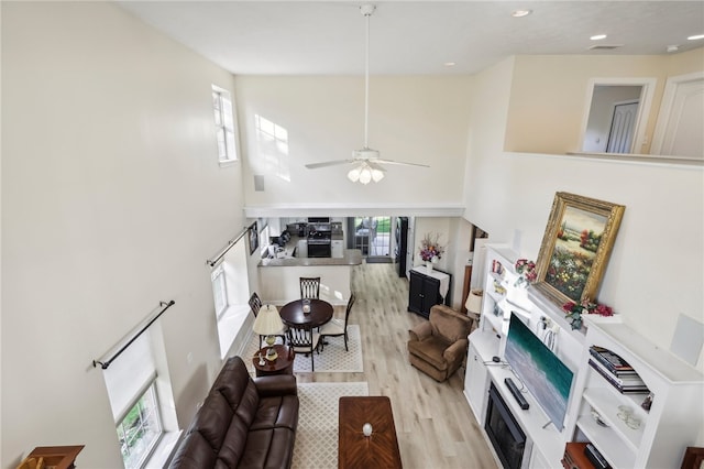 living room with light hardwood / wood-style flooring, a healthy amount of sunlight, and ceiling fan