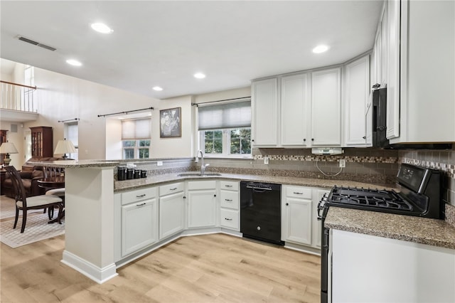 kitchen featuring kitchen peninsula, white cabinets, black appliances, light hardwood / wood-style floors, and sink