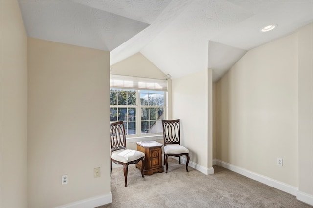 sitting room featuring a textured ceiling, light colored carpet, and vaulted ceiling