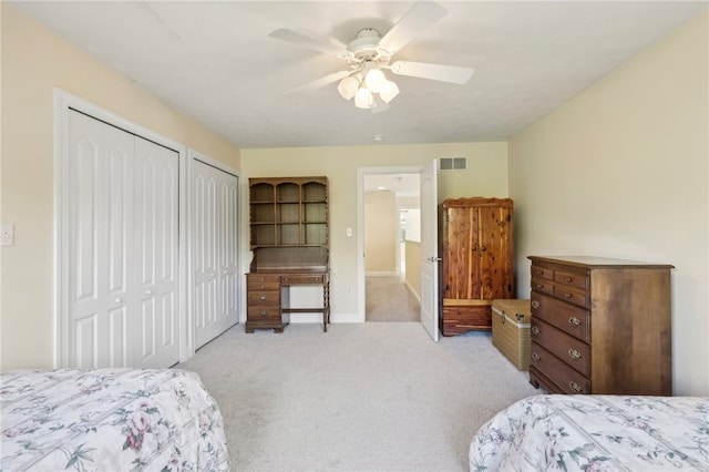 carpeted bedroom featuring two closets and ceiling fan