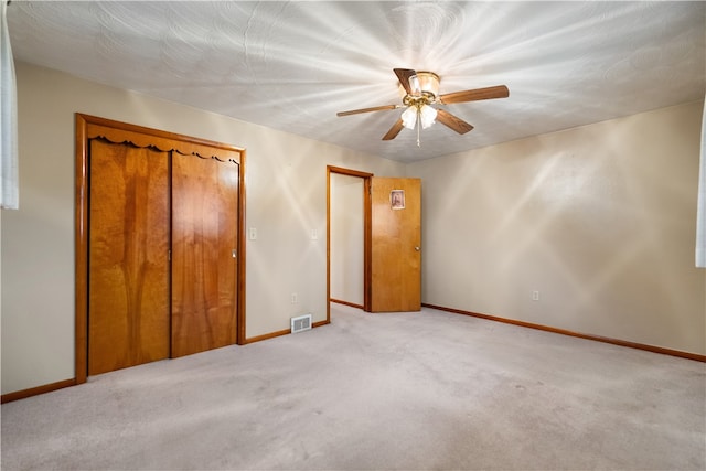 unfurnished bedroom with a closet, ceiling fan, and light colored carpet