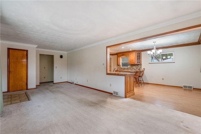 unfurnished living room with light carpet, a notable chandelier, and ornamental molding