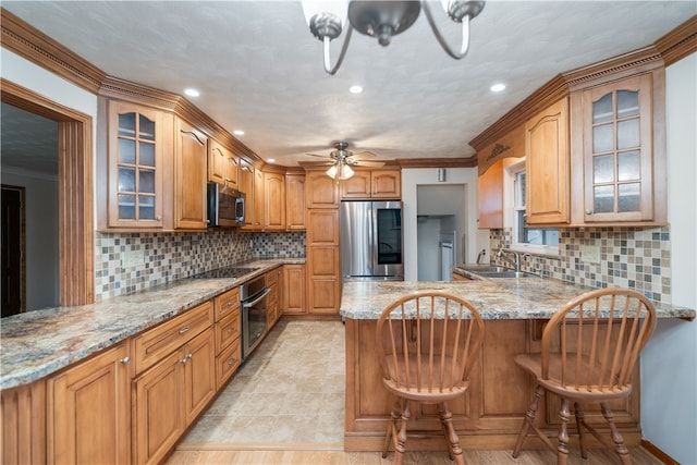 kitchen featuring appliances with stainless steel finishes, backsplash, kitchen peninsula, crown molding, and a breakfast bar area