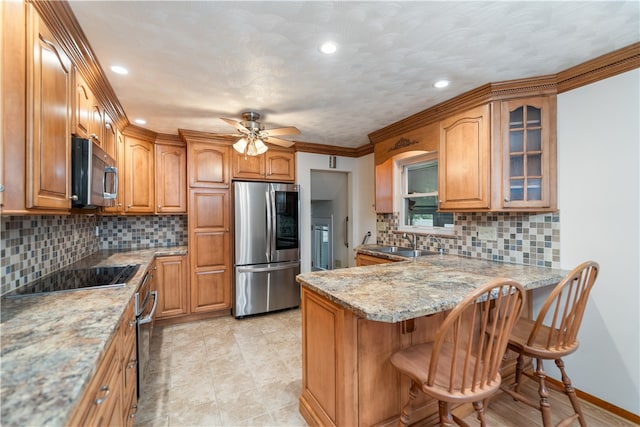 kitchen with appliances with stainless steel finishes, kitchen peninsula, decorative backsplash, and a breakfast bar area