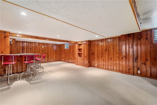 bar with a textured ceiling, carpet flooring, and wood walls