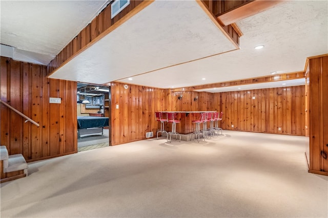 interior space with a textured ceiling, carpet floors, and wood walls