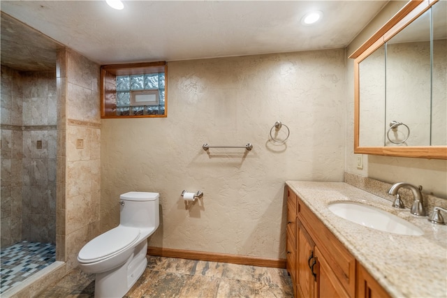 bathroom featuring toilet, vanity, and a tile shower