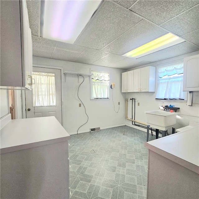 kitchen with white cabinetry, a drop ceiling, and sink