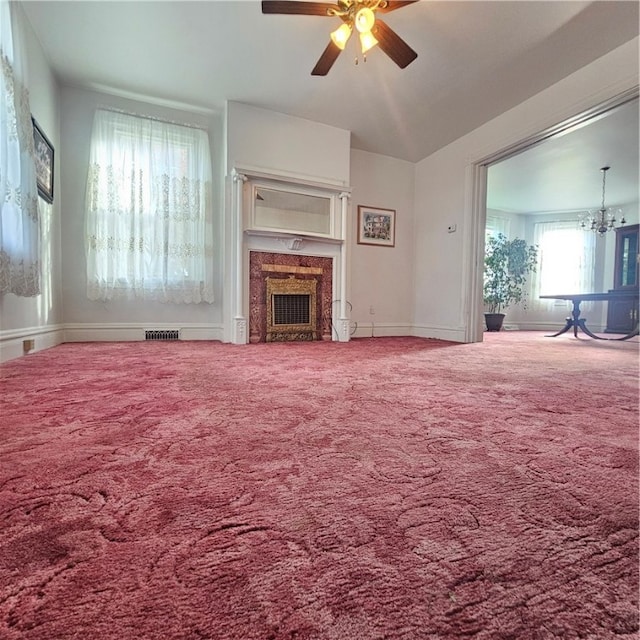 unfurnished living room with carpet flooring, vaulted ceiling, and ceiling fan with notable chandelier