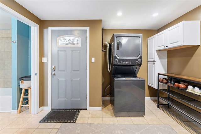 laundry area with stacked washer / drying machine and light tile patterned flooring