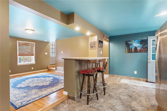 bar featuring light hardwood / wood-style flooring and stainless steel fridge