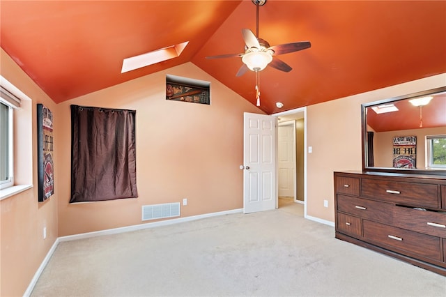 unfurnished bedroom featuring lofted ceiling with skylight, light colored carpet, and ceiling fan