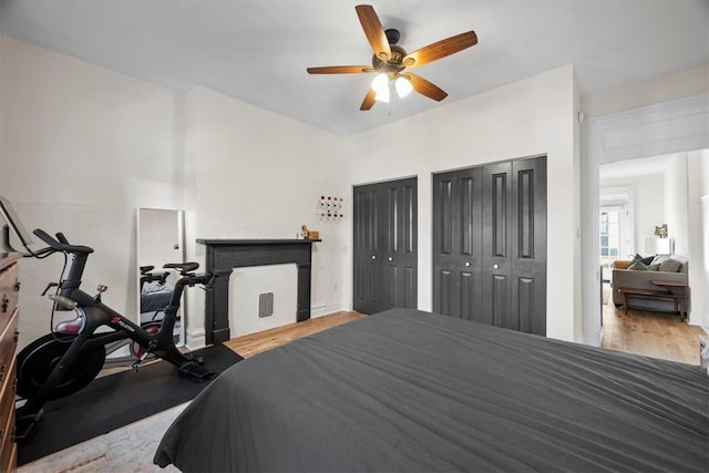 bedroom featuring ceiling fan, light wood-type flooring, and two closets