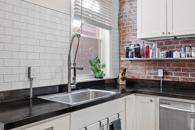 kitchen featuring stainless steel dishwasher, sink, decorative backsplash, and white cabinetry