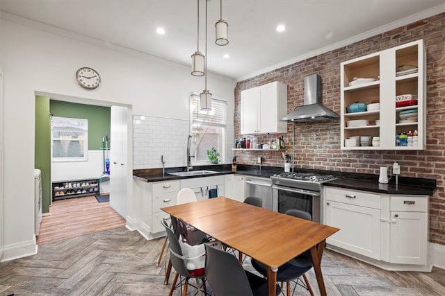 kitchen featuring wall chimney range hood, white cabinetry, light parquet flooring, and hanging light fixtures