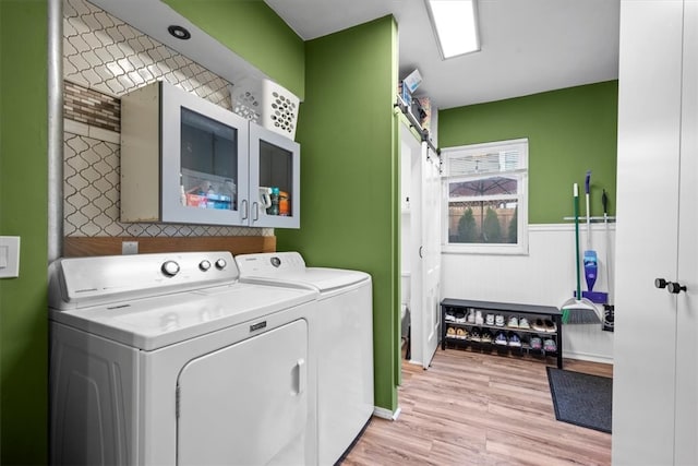 laundry room featuring washing machine and clothes dryer, light wood-type flooring, and cabinets