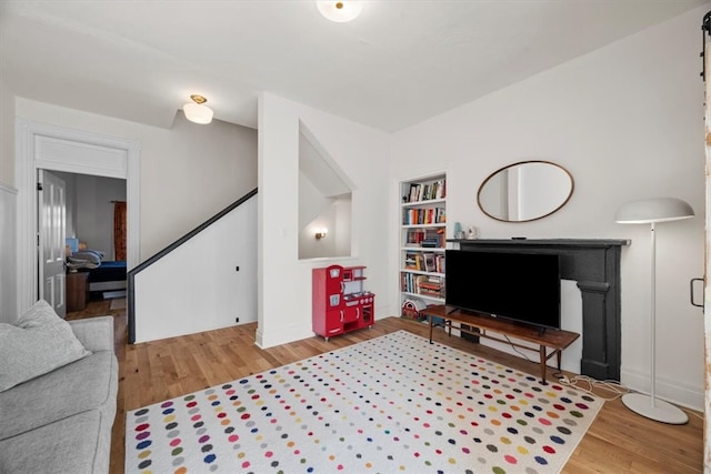 living room featuring built in shelves and wood-type flooring