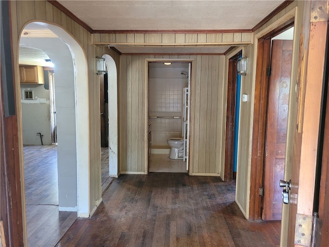 hall featuring crown molding, wood walls, and dark hardwood / wood-style flooring