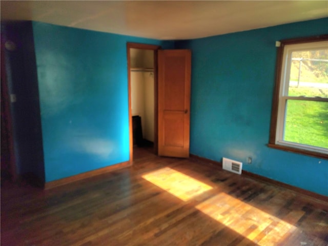 unfurnished bedroom with dark wood-type flooring and a closet