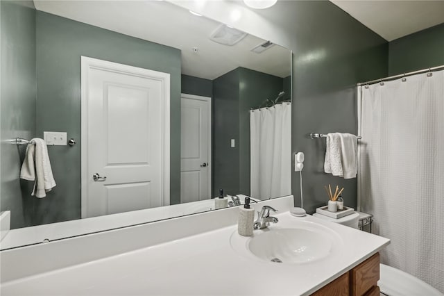 bathroom featuring vanity, walk in shower, and toilet