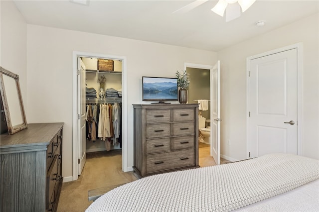 bedroom featuring light carpet, ceiling fan, a closet, ensuite bathroom, and a walk in closet