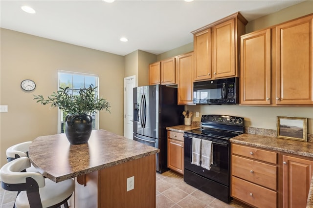 kitchen featuring black appliances, a center island, and a breakfast bar