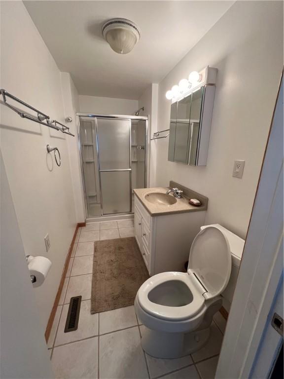 bathroom with toilet, tile patterned flooring, vanity, and walk in shower