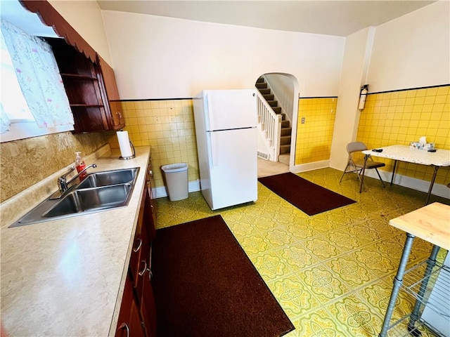 kitchen featuring white refrigerator, tile walls, and sink