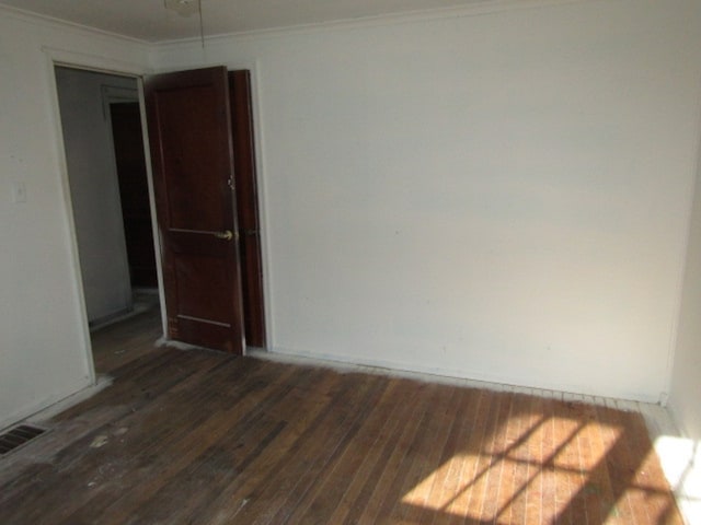 unfurnished room with dark wood-type flooring and crown molding