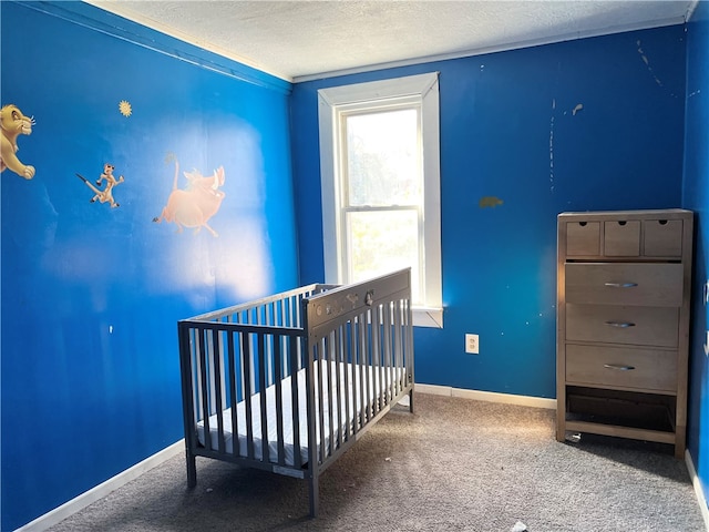 bedroom featuring crown molding, a textured ceiling, a crib, and carpet