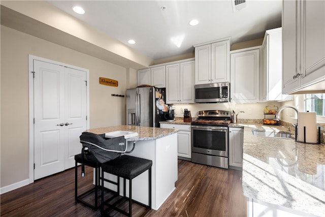 kitchen with white cabinets, a kitchen island, appliances with stainless steel finishes, dark wood-type flooring, and sink